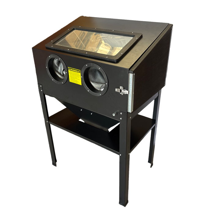 A black metal sandblast cabinet on a matching stand, featuring a top viewing window, two circular air intake ports with black glovescreens, a yellow warning label, and a lower shelf, shown against a plain white background.