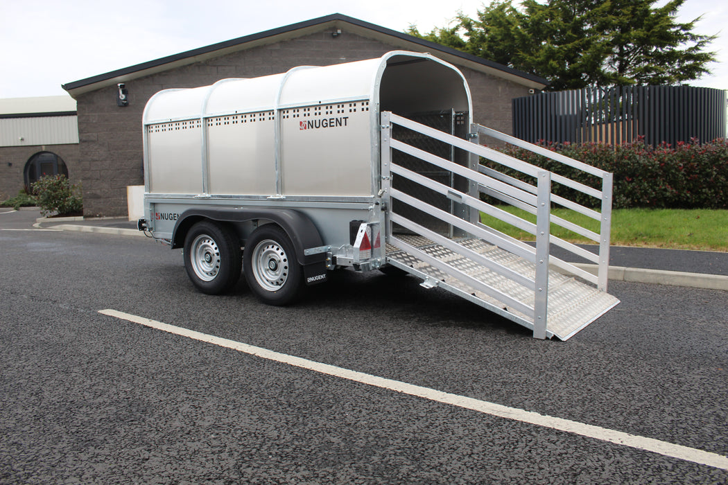 Silver livestock trailer with open side door on a paved surface.